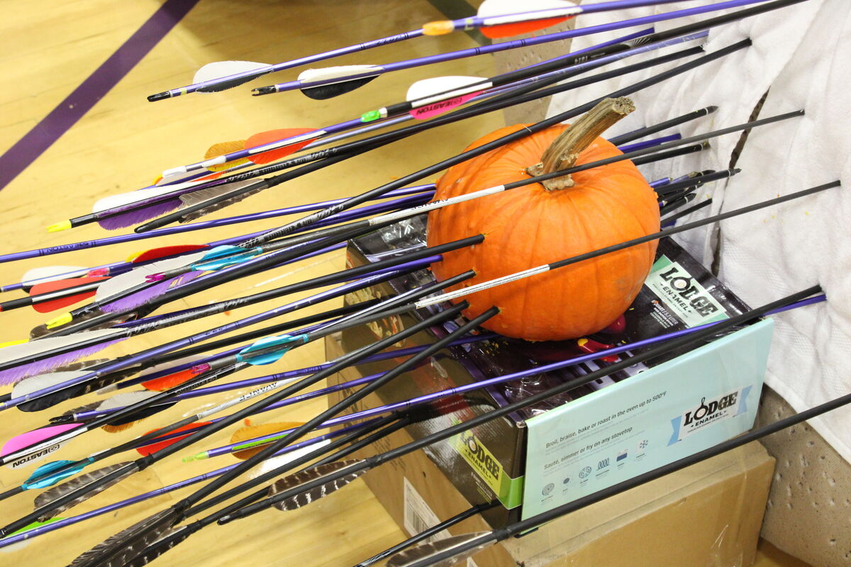 A pumpkin on a target, surrounded by arrows, at a Halloween practice