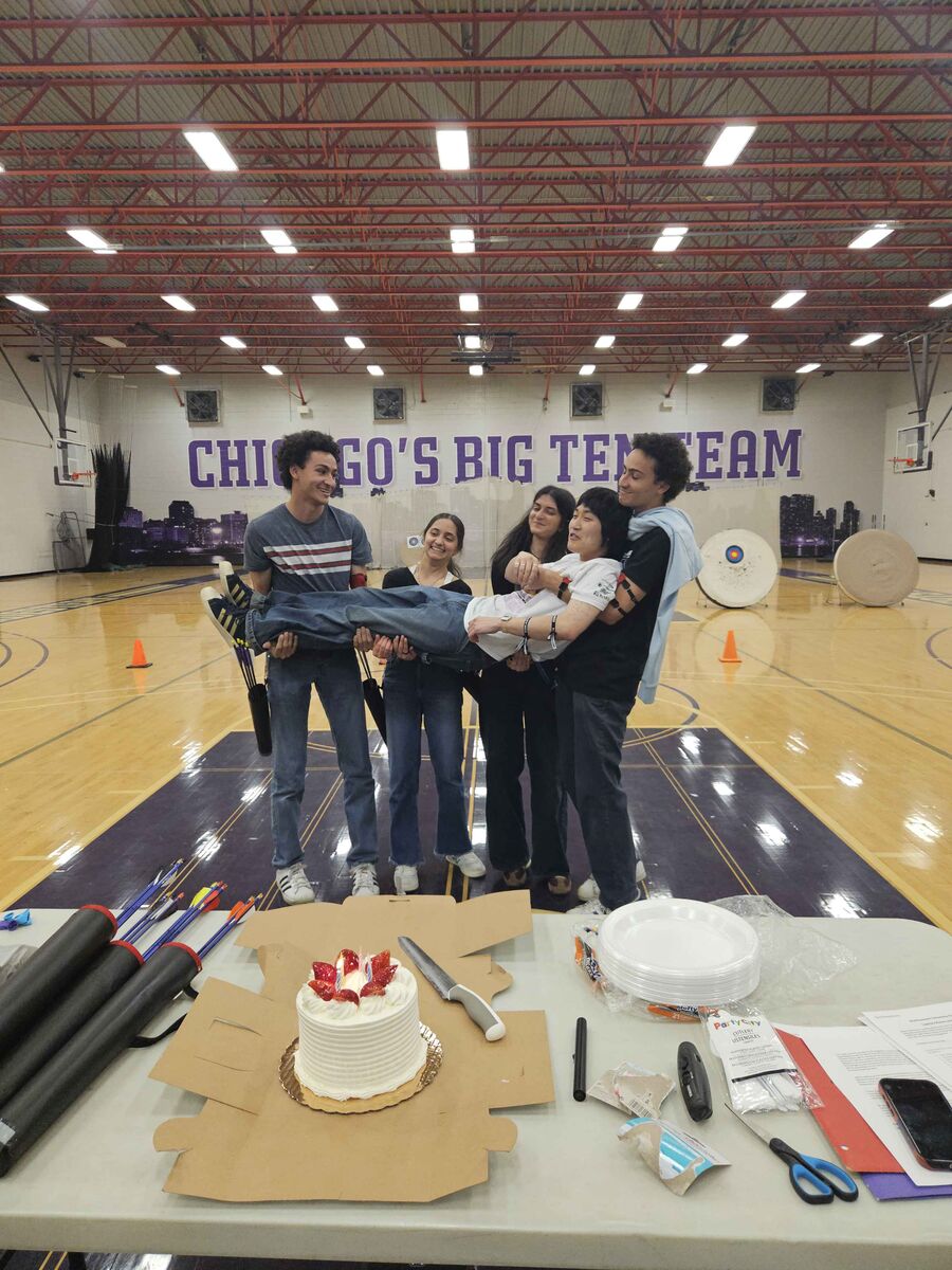 Club members lifting a graduating senior at a celebration with cake
